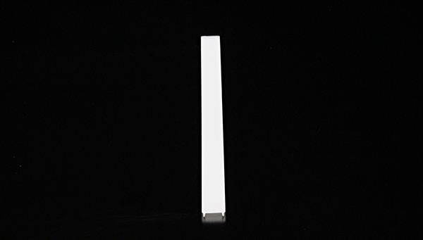 Pojedynczy, biały, podłużny przedmiot leży pośrodku czarnego tła.