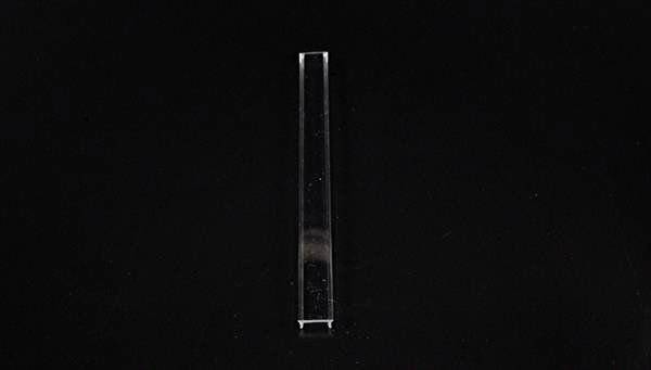 Pojedynczy, wąski, przezroczysty obiekt szklany na czarnym tle.