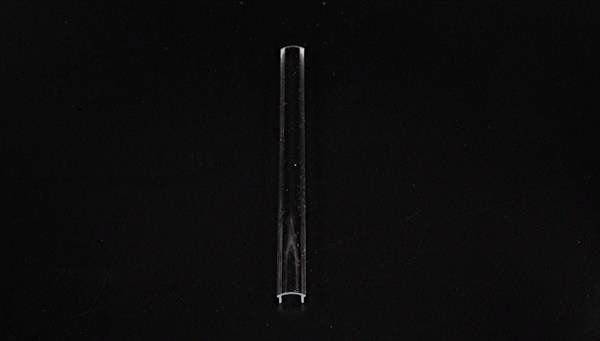 Pojedyncza, przezroczysta szklana rurka ustawiona w pozycji pionowej na czarnym tle.