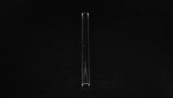 Przezroczysty pręt szklany stoi pionowo na czarnym tle.