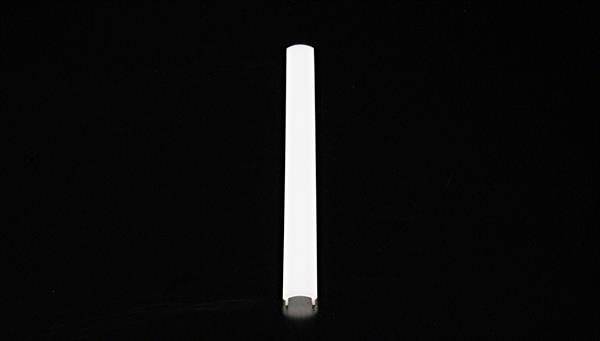 Długi, biały, cylindryczny przedmiot leży poziomo na czarnym tle.