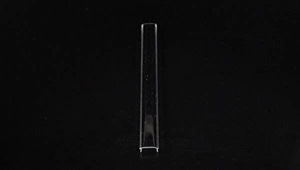 Przezroczysta, pusta probówka leży pionowo na czarnym tle.