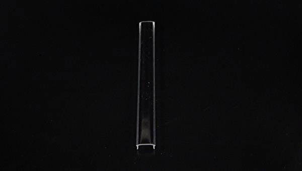 Przezroczysta rura z tworzywa sztucznego leży na czarnym tle.