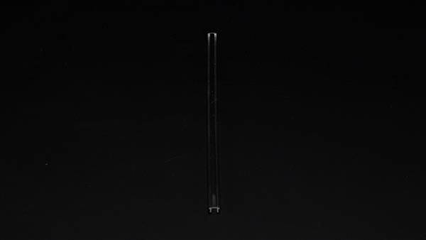 Pojedynczy, cienki pręt stoi pionowo na czarnym tle.