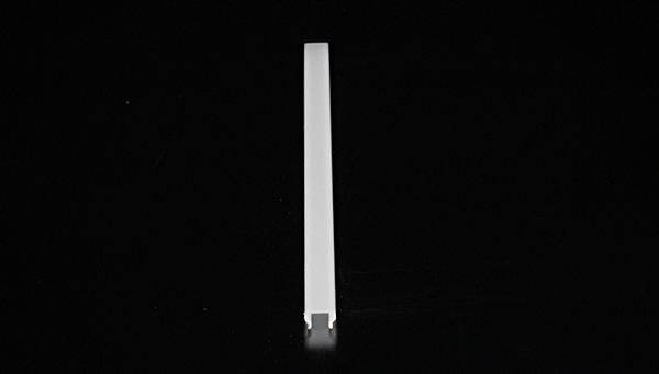 Pojedynczy biały, podłużny słup stoi pionowo na czarnym tle.