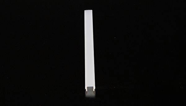 Pojedynczy biały prostopadłościenny pręt stoi pionowo na czarnej powierzchni, umieszczony centralnie w kadrze.
