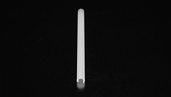 Długi, biały, cylindryczny przedmiot leży na czarnym tle.