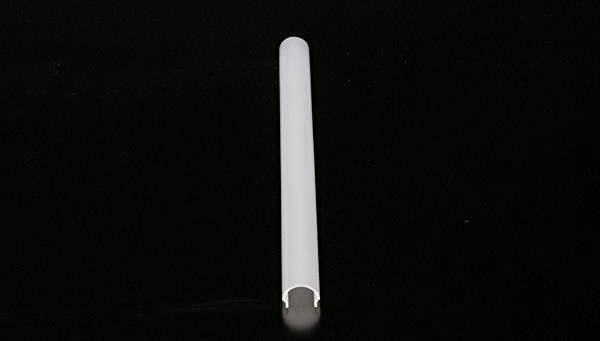 Biała, pusta tuleja lub rura leży poziomo na czarnym tle.