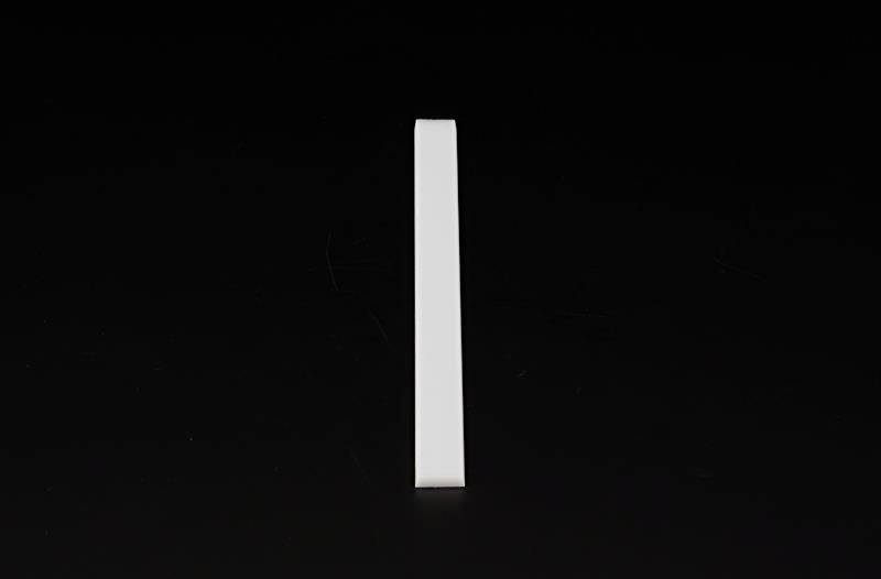 Pojedynczy biały obiekt stoi pionowo na czarnym tle.