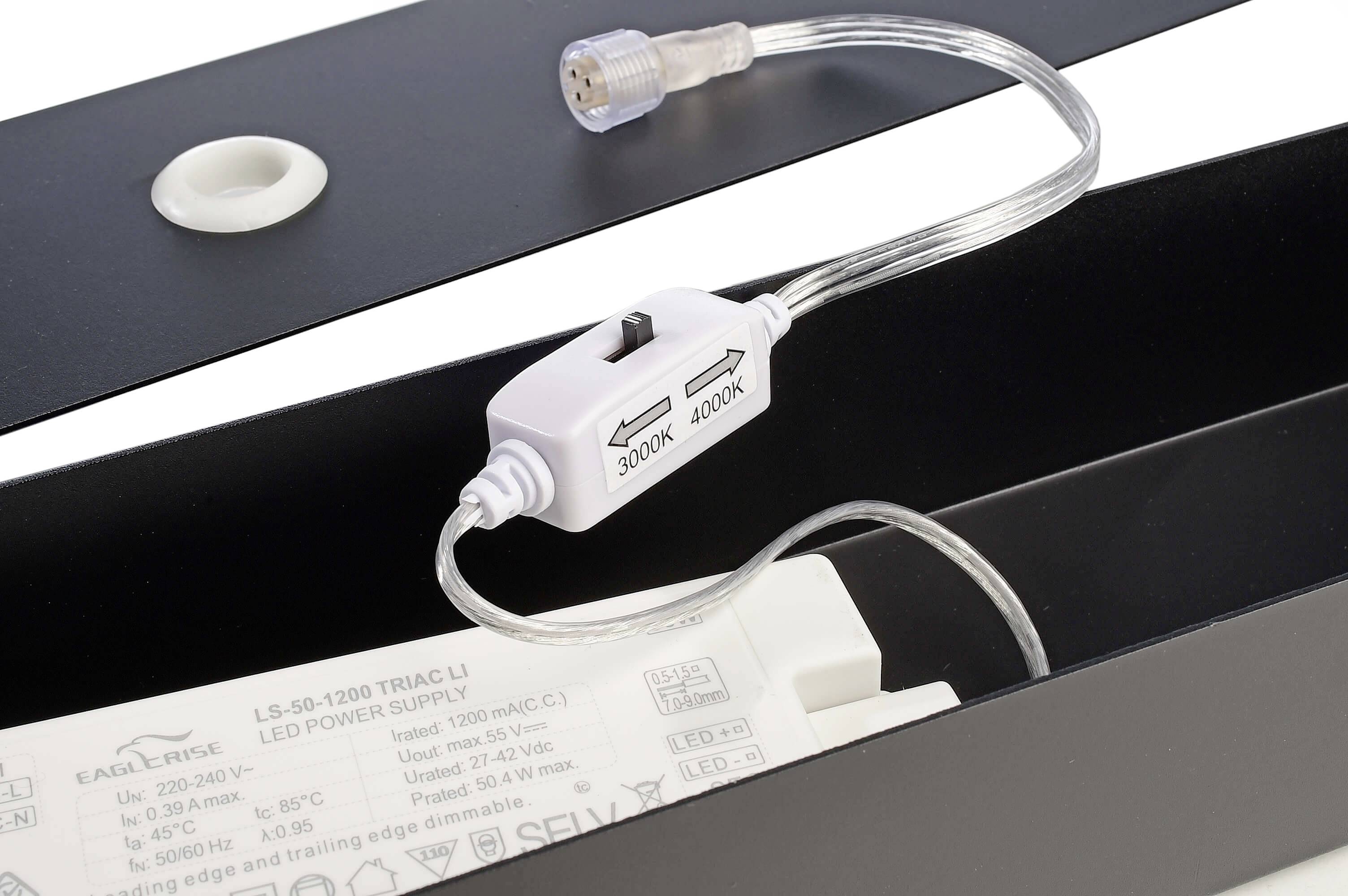 Wtyczka z przełącznikiem między 3000K a 4000K do lamp LED, kabel w kolorze beżowym. W tle widoczne części opraw LED.