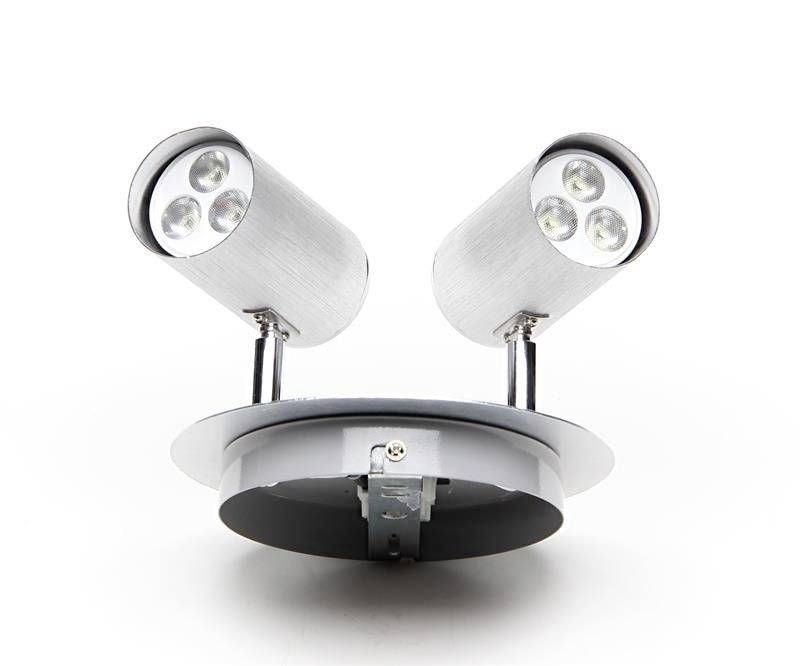 Dwie srebrne cylindryczne lampy LED na okrągłej podstawie, świecące w przeciwnych kierunkach.