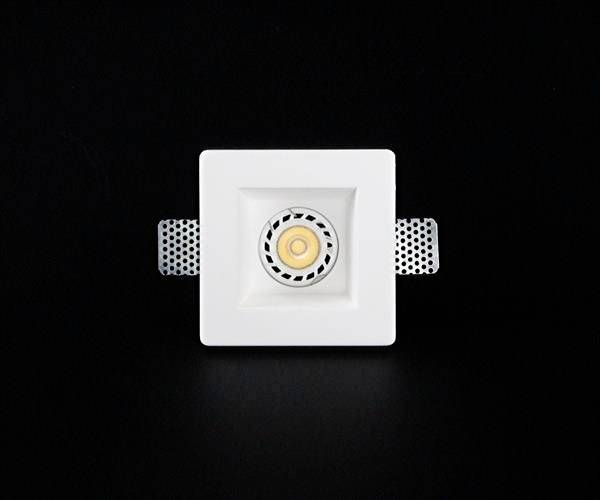 Kwadratowy spot LED w białej oprawie na czarnym tle. Nadaje się do montażu sufitowego i posiada boczne uchwyty.
