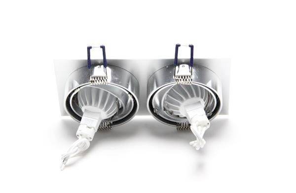 Dwa regulowane podtynkowe reflektory LED w okrągłych oprawach na białym stelażu, odpowiednie do montażu sufitowego.