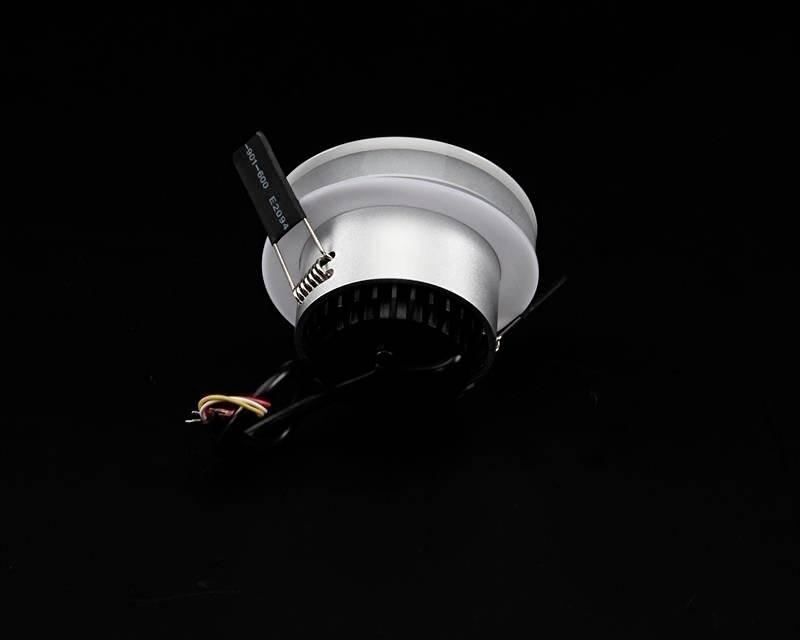 Reflektor w czarnej obudowie z kablami, na czarnym tle.