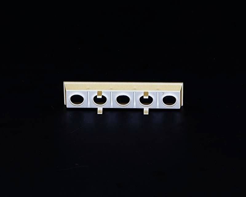 Biała listwa z pięcioma równomiernie rozmieszczonymi okrągłymi otworami. Znajduje się na czarnym tle.