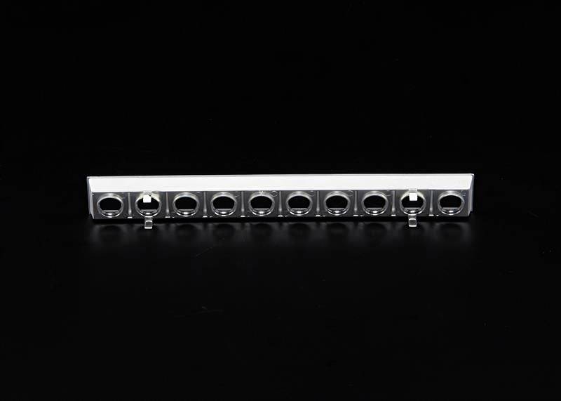 Srebrna metalowa szyna z dziesięcioma równomiernie rozmieszczonymi otworami w kształcie kół na czarnym tle.