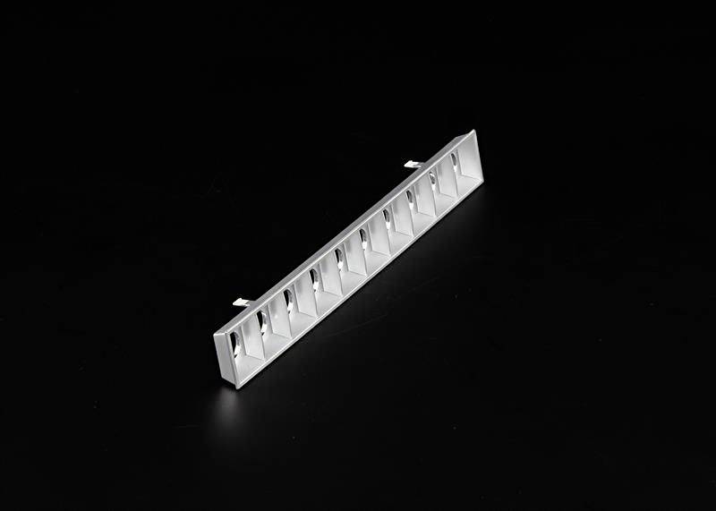 Biała, prostokątna osłona wentylacyjna z wieloma równomiernymi szczelinami na czarnym tle.