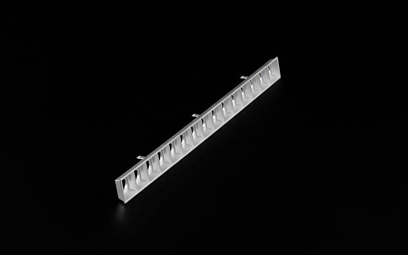 Długi, srebrny element metalowy o prostokątnym kształcie na czarnym tle, prawdopodobnie część urządzenia technicznego.
