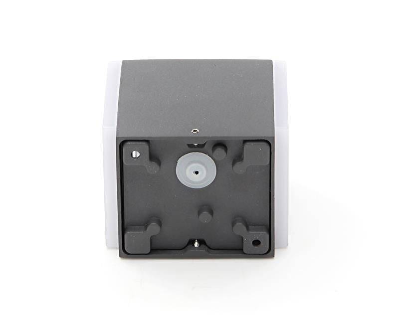 Widok z tyłu czarnego, sześciennego urządzenia z białym przyciskiem i czterema gumowymi stopkami.