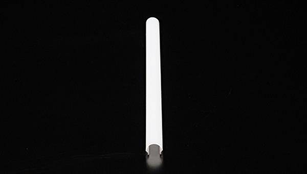 Długi, biały, cylindryczny przedmiot leży poziomo na czarnym tle.