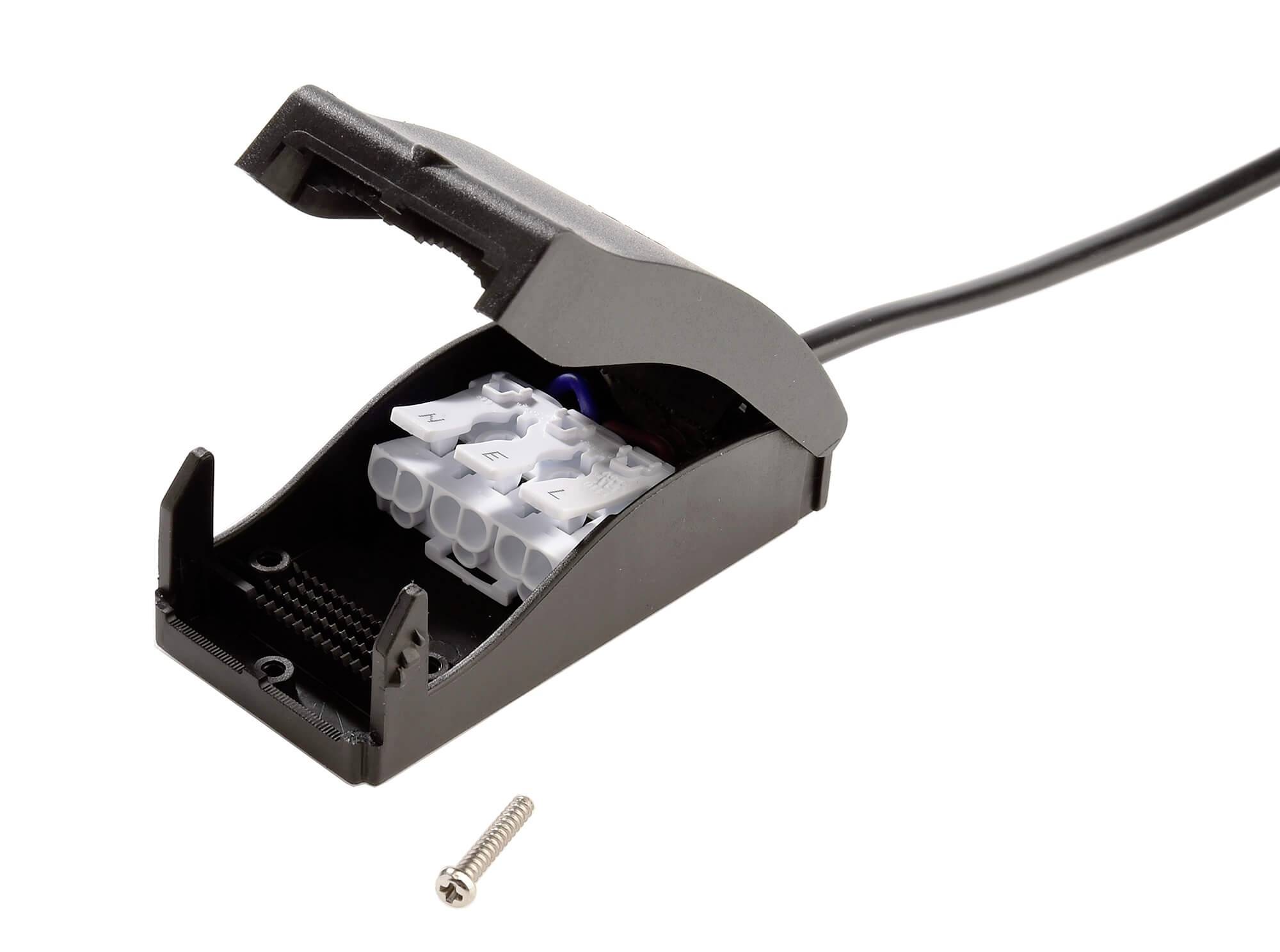 Czarna rozgałęźna puszka kablowa z otwartą pokrywą, widoczne białe zaciski połączeniowe wewnątrz. Przed nią leży jedna śruba.