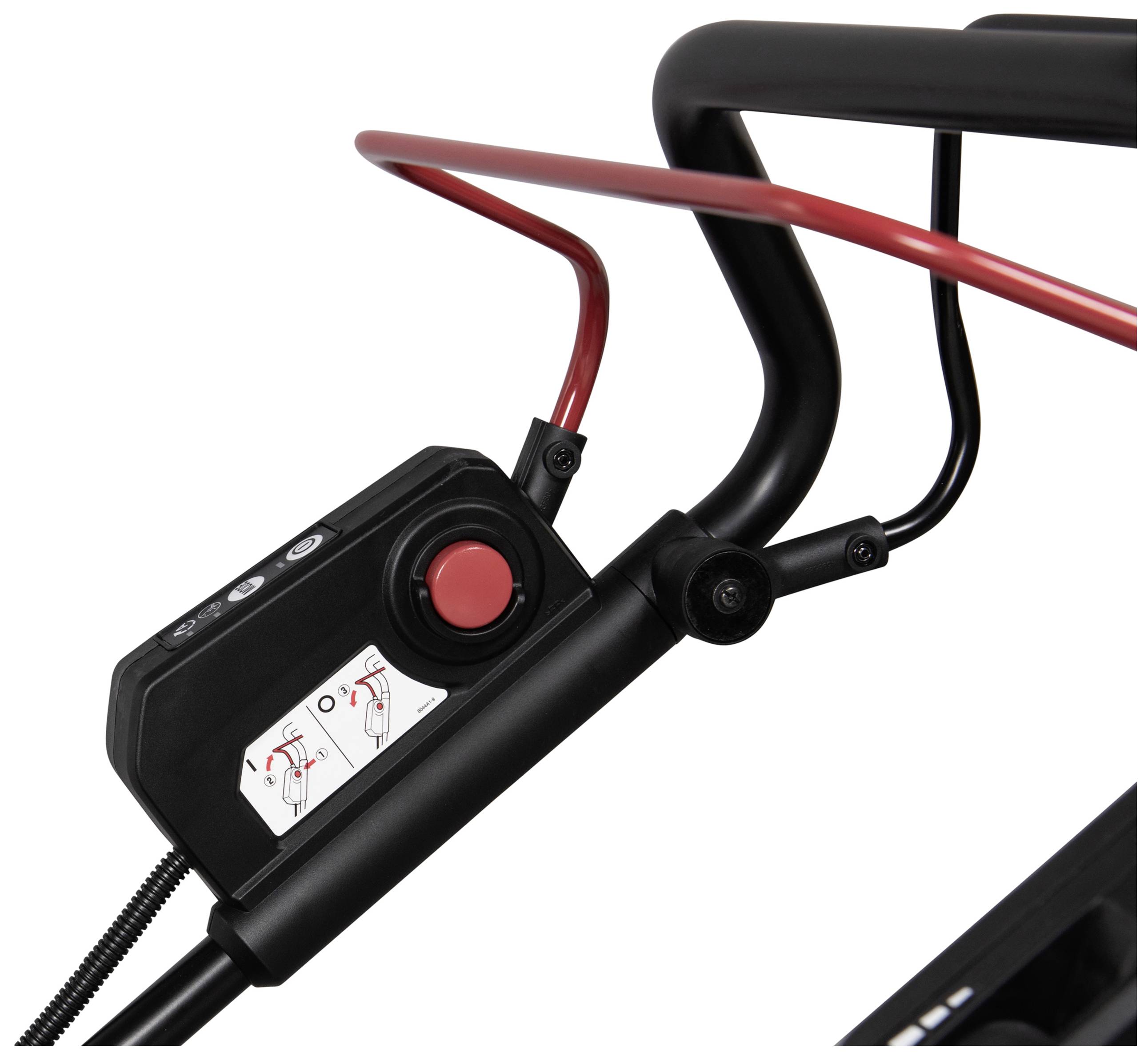 Zbliżenie czarnej rękojeści kosiarki z czerwoną dźwignią oraz panelem sterowania z przyciskiem i instrukcjami obsługi.