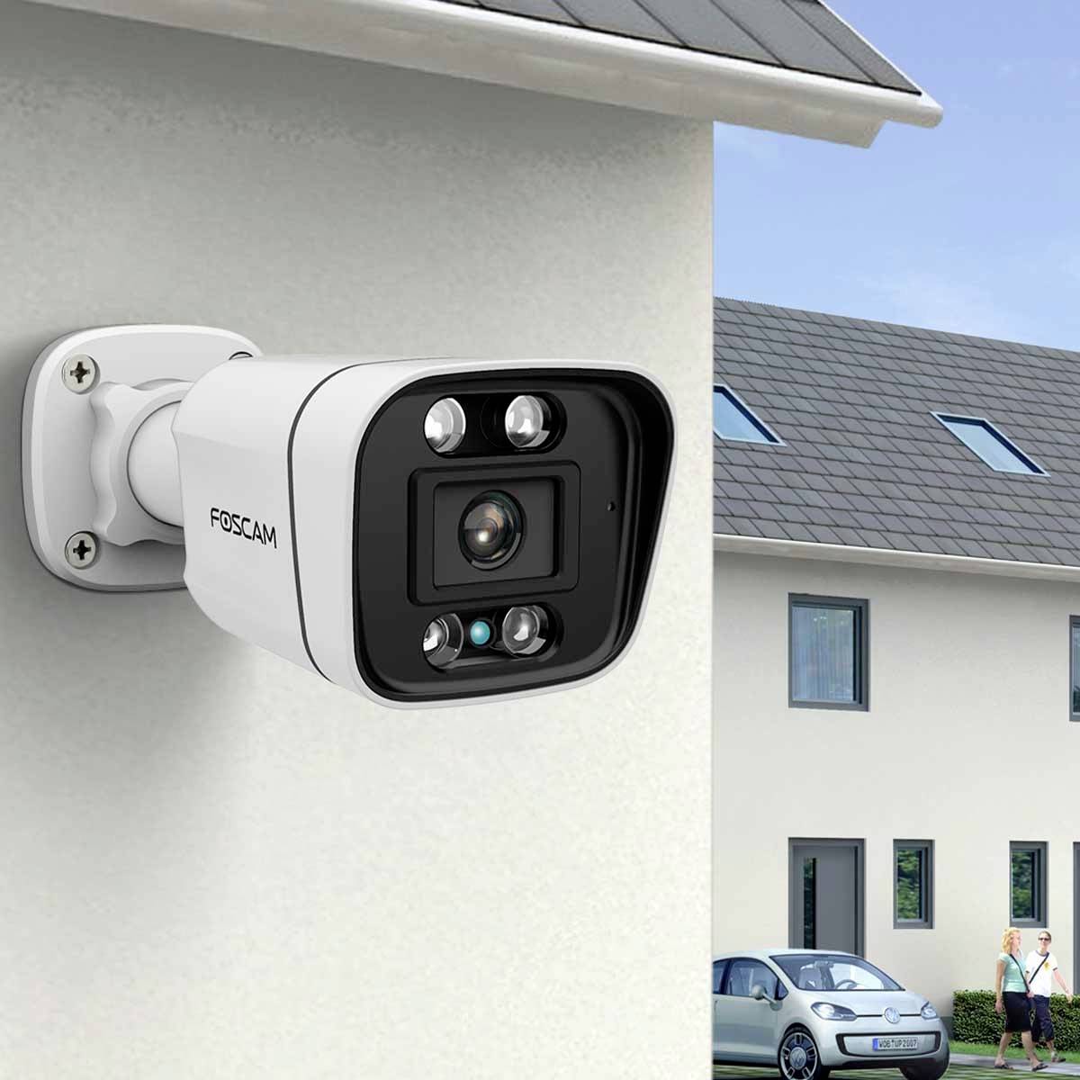 Kamera monitorująca zamontowana na外ściance zewnętrznej domu, skierowana na samochód i sąsiedni budynek w świetle dziennym.