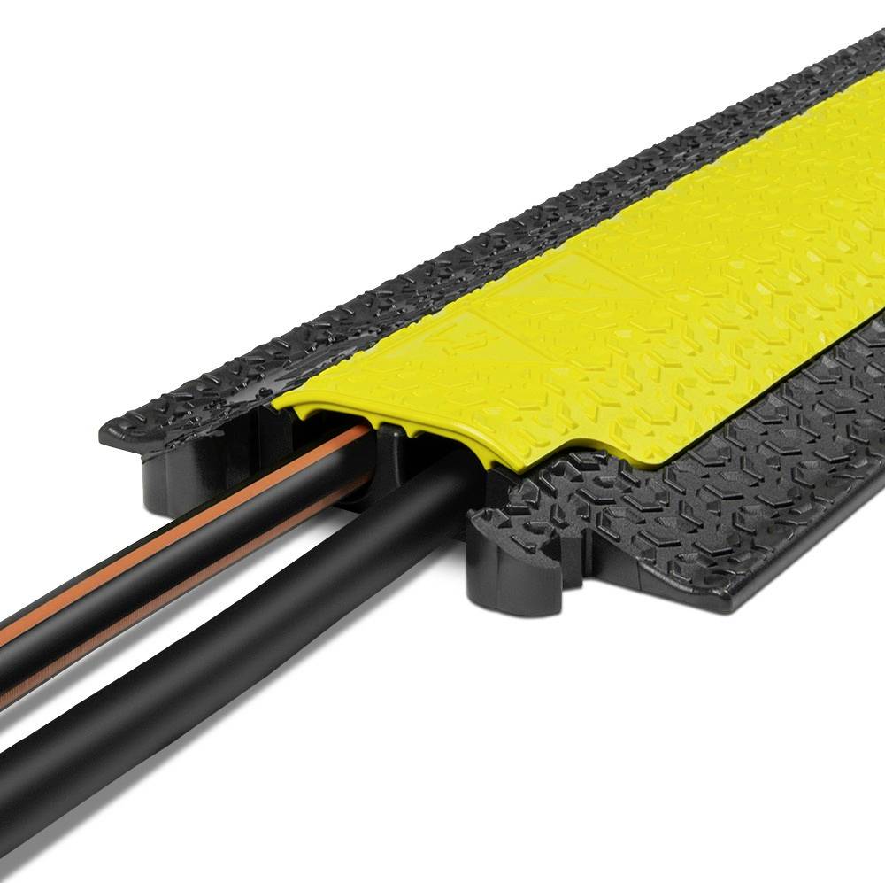 Czarny mostek kablowy z żółtą pokrywą, który chroni i porządkuje dwa kable. Idealny do zastosowań w ruchu drogowym lub strefach przemysłowych.