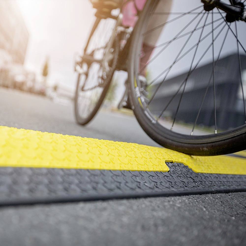 Rowerzysta jedzie oznakowaną ścieżką rowerową. Przednie koło roweru jest ostre, podczas gdy tło jest rozmyte.