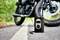 Przenośny kompresor do opon wyświetla '2.40', stojąc na drodze przed motocyklem.