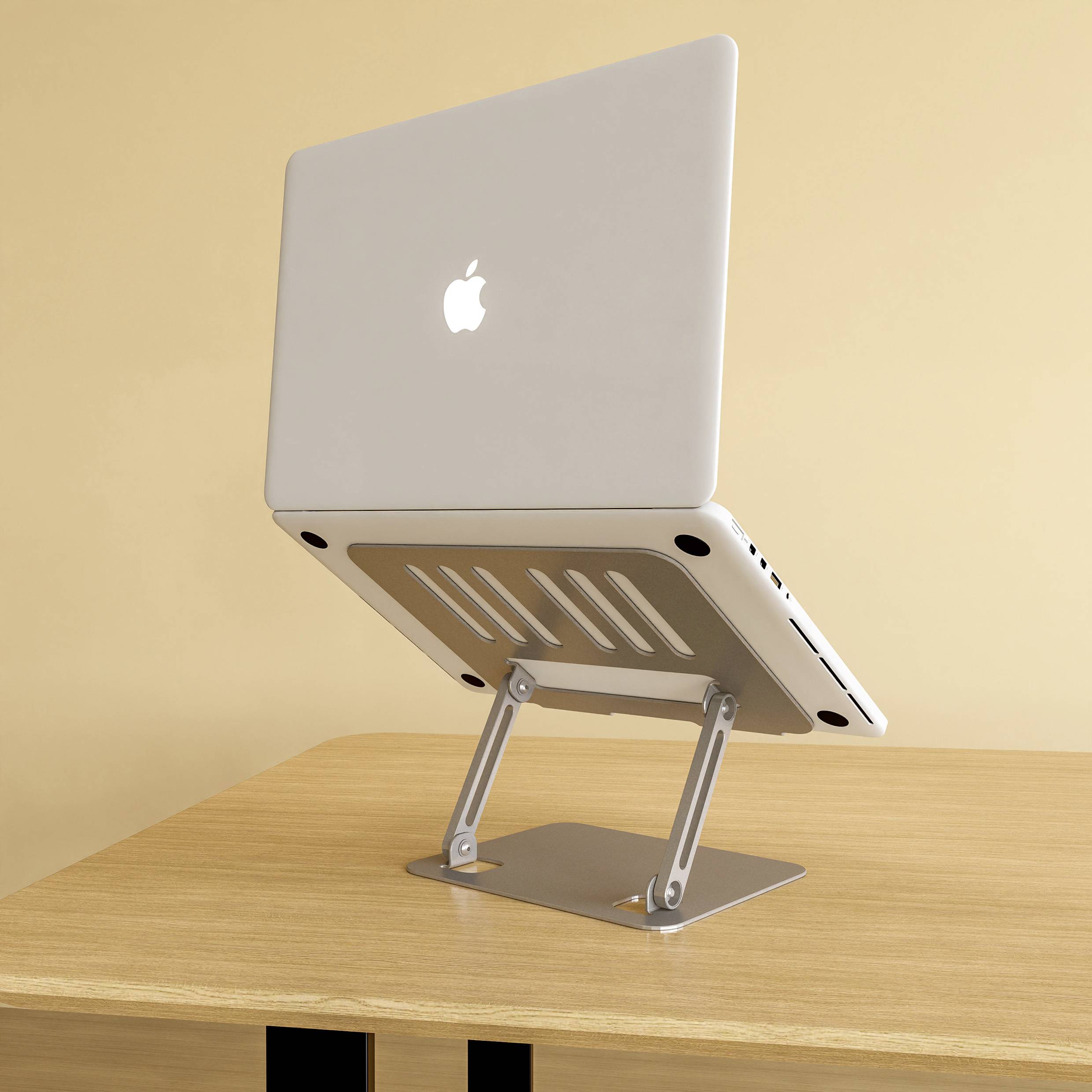 Laptop stoi na regulowanym stojaku aluminiowym na drewnianym stole. Ekran jest częściowo otwarty.