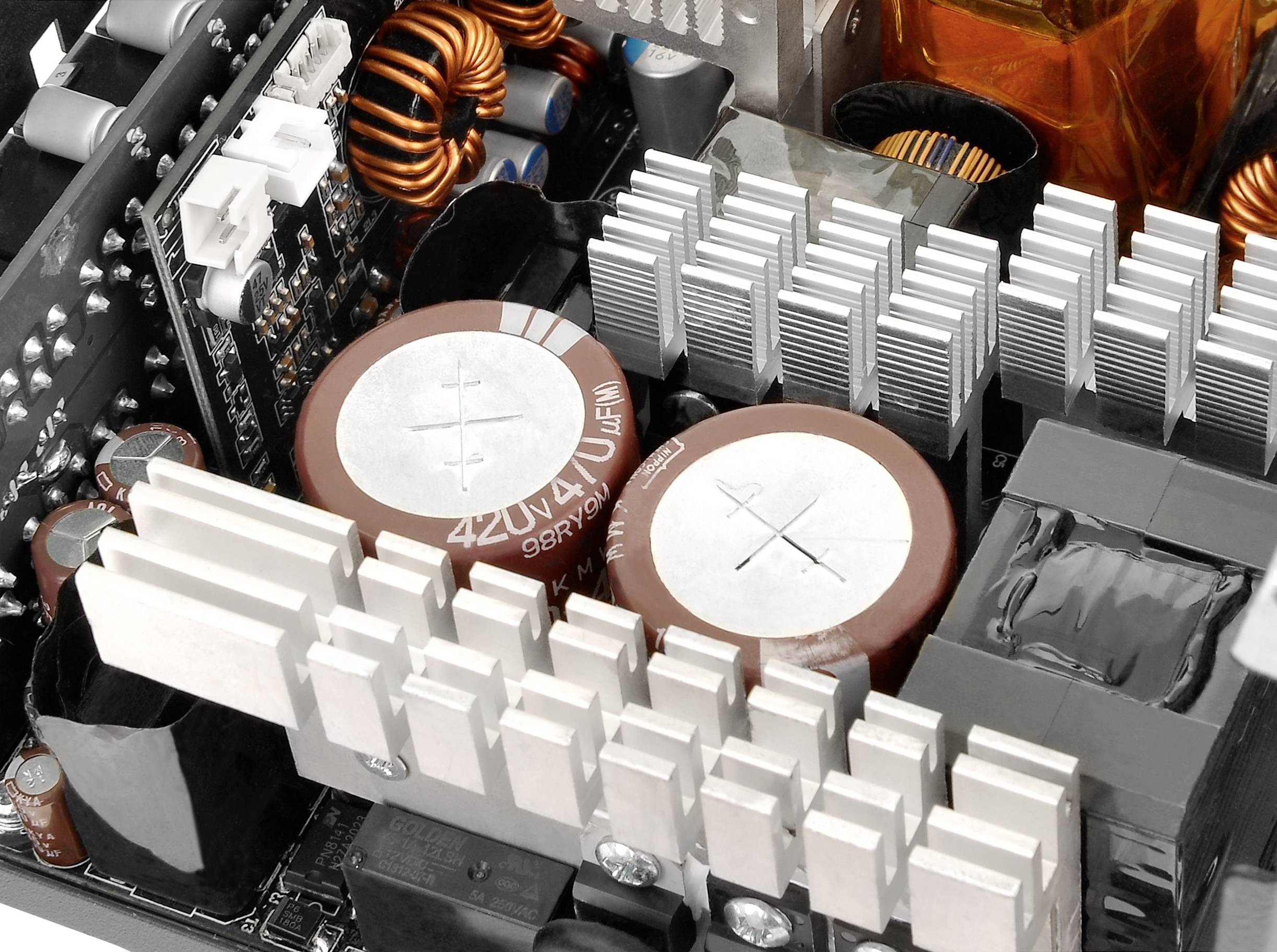 Zbliżenie płyty głównej komputera z dużymi kondensatorami i radiatorami. Widoczne są różne komponenty elektroniczne.