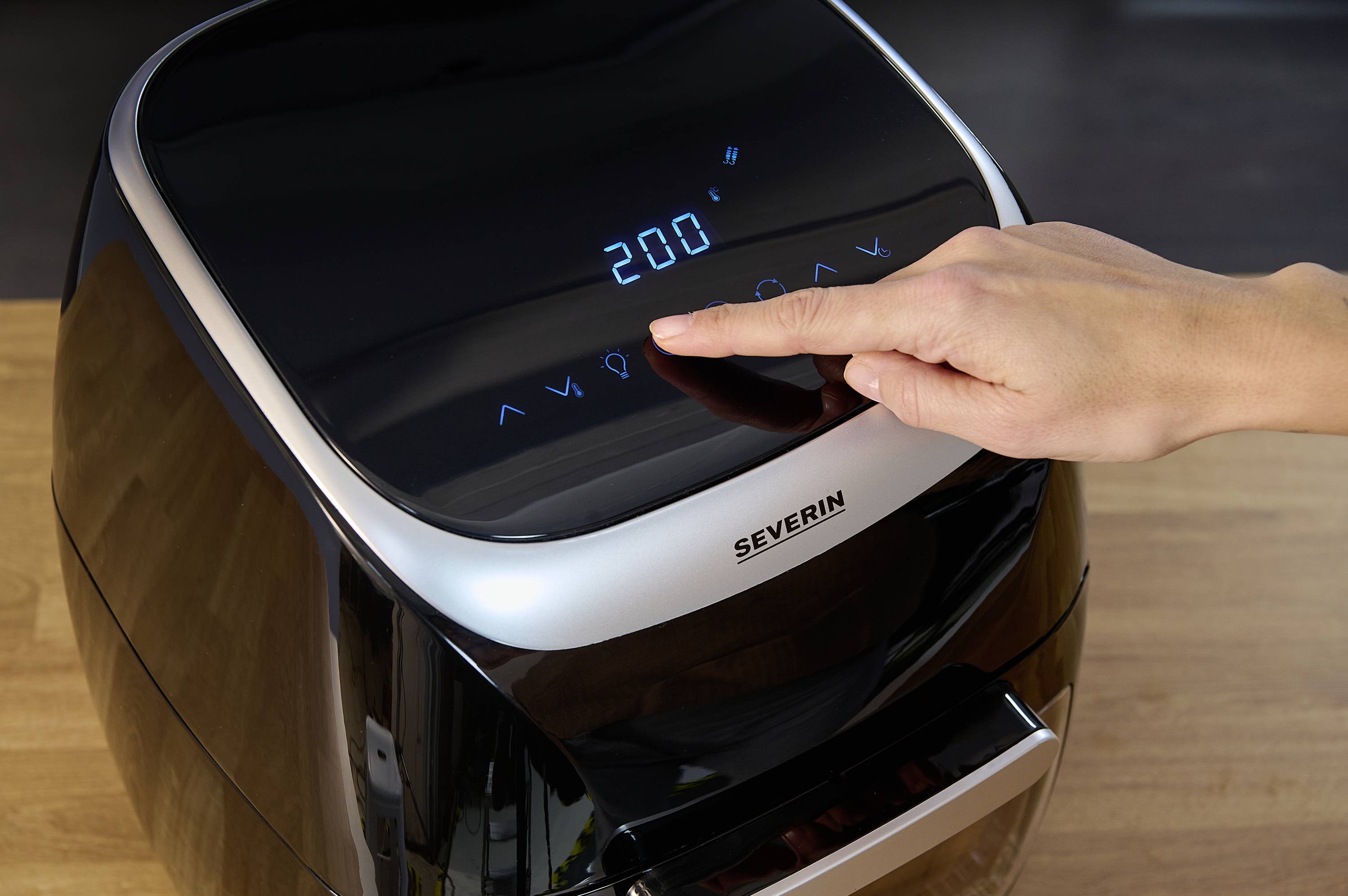 Osoba obsługuje frytkownicę beztłuszczową, ustawiając temperaturę 200 stopni Celsjusza za pomocą cyfrowego wyświetlacza.