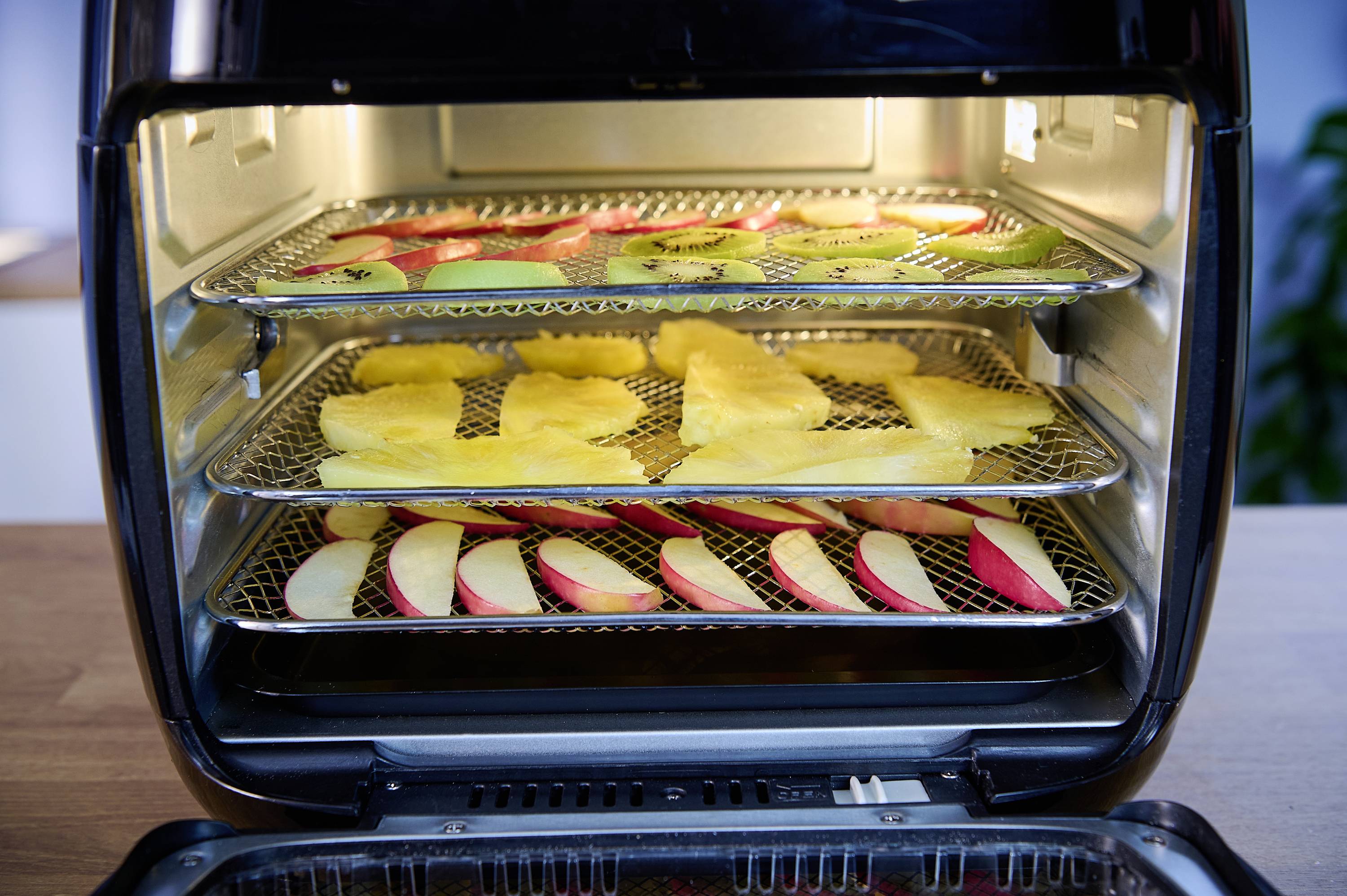 'Otwarty piec z trzema wkładami. Na górze plastry jabłek i kiwi, w środku plastry ananasa, na dole plastry jabłek.'