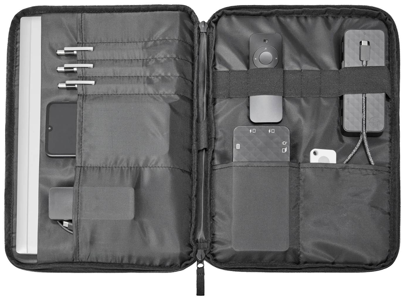 Czarna torba otwarta, z elementami organizacyjnymi: długopisy, pilot, ładowarka i kable są starannie ułożone.