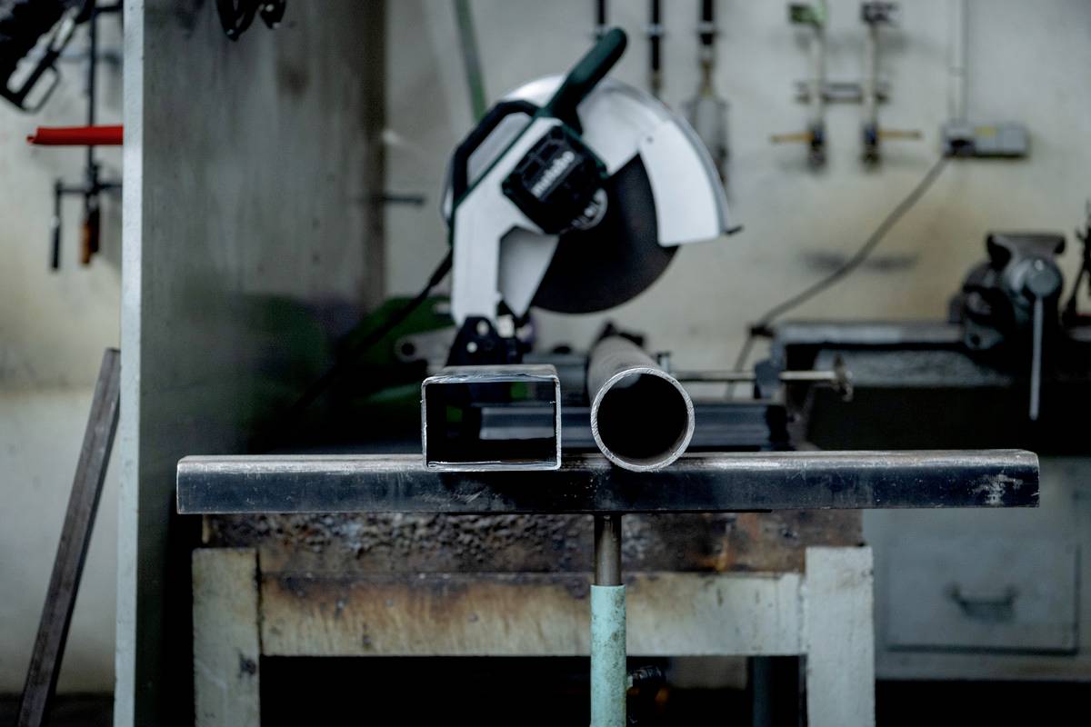 Warsztat z rurą ok, po lewej stronie i maszyną w tle; widoczne przemysłowe środowisko pracy do obróbki metalu.