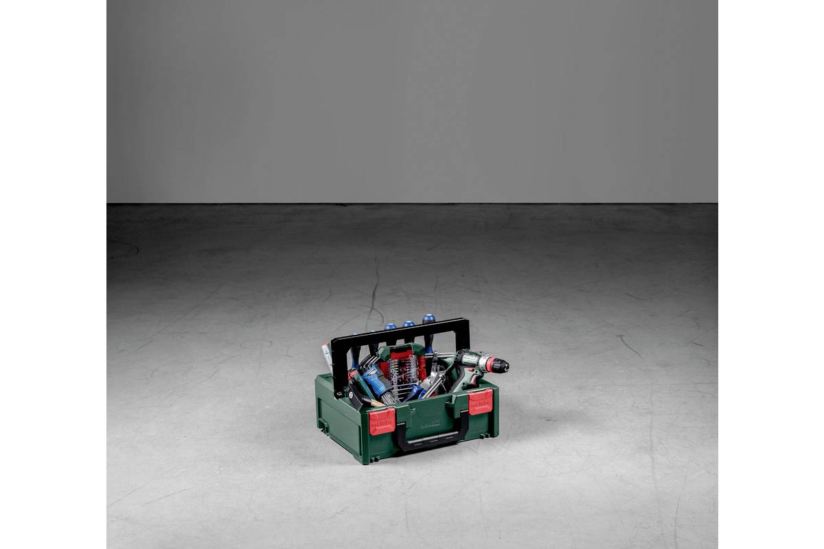 Otwarta zielona skrzynka narzędziowa stoi na szarym podłożu, wypełniona różnymi narzędziami ręcznymi, w tym śrubokrętami i szczypcami.