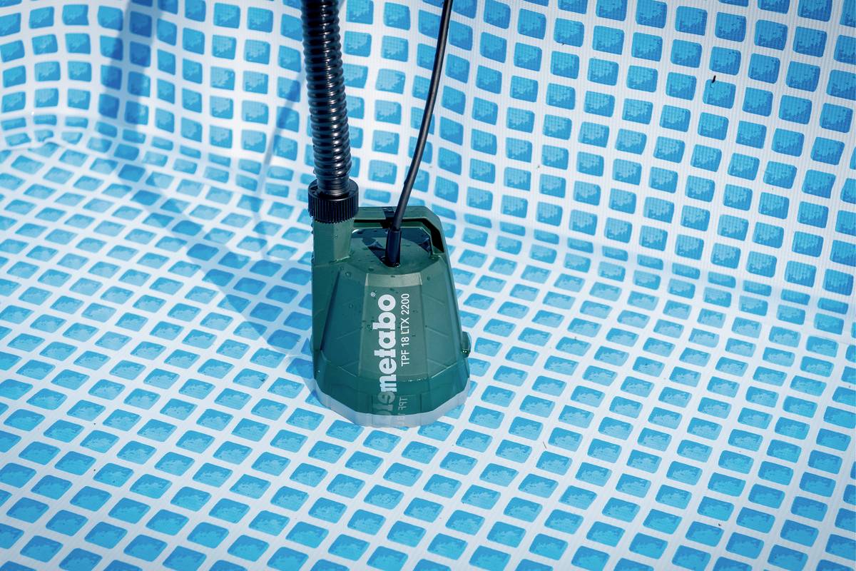 Zielona pompa zanurzeniowa Metabo stoi na niebiesko-biało kratowanej podłodze basenu, gotowa do odpompowania wody.