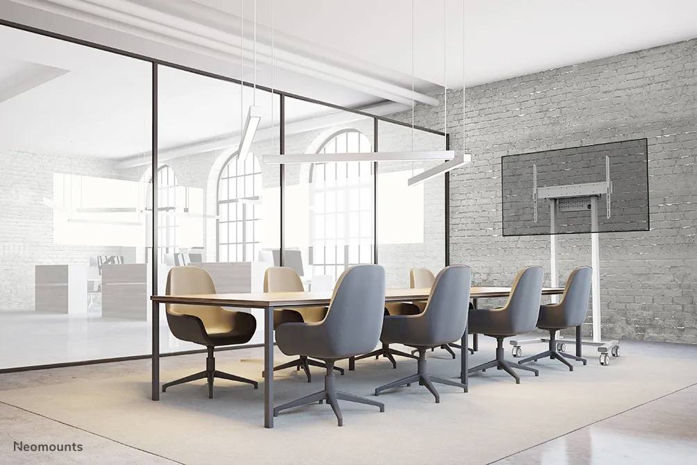 Nowoczesna sala konferencyjna z dużym drewnianym stołem i kilkoma niebieskimi krzesłami. Na ścianach znajdują się duże okna i ekran.