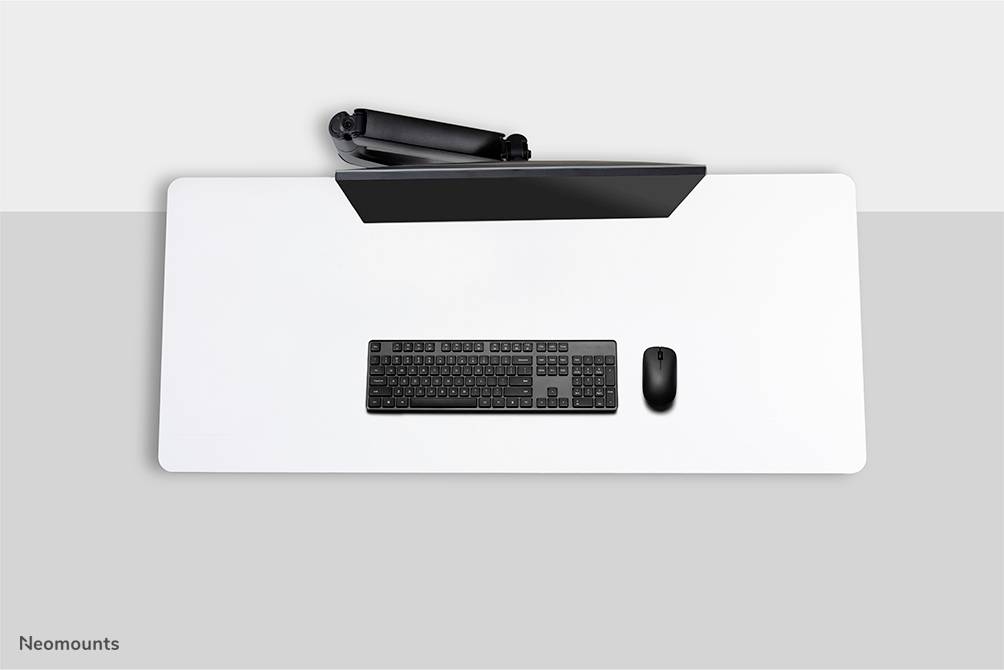 Widok z góry na biurko: klawiatura, mysz i płaski ekran na białym stole. Minimalistyczna, uporządkowana aranżacja.