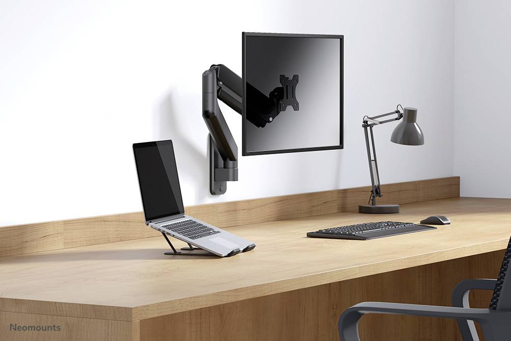 Biurko z podstawką pod laptopa, laptopem, uchwytem na monitor, monitorem umieszczonym nad nim, klawiaturą i lampką biurkową.