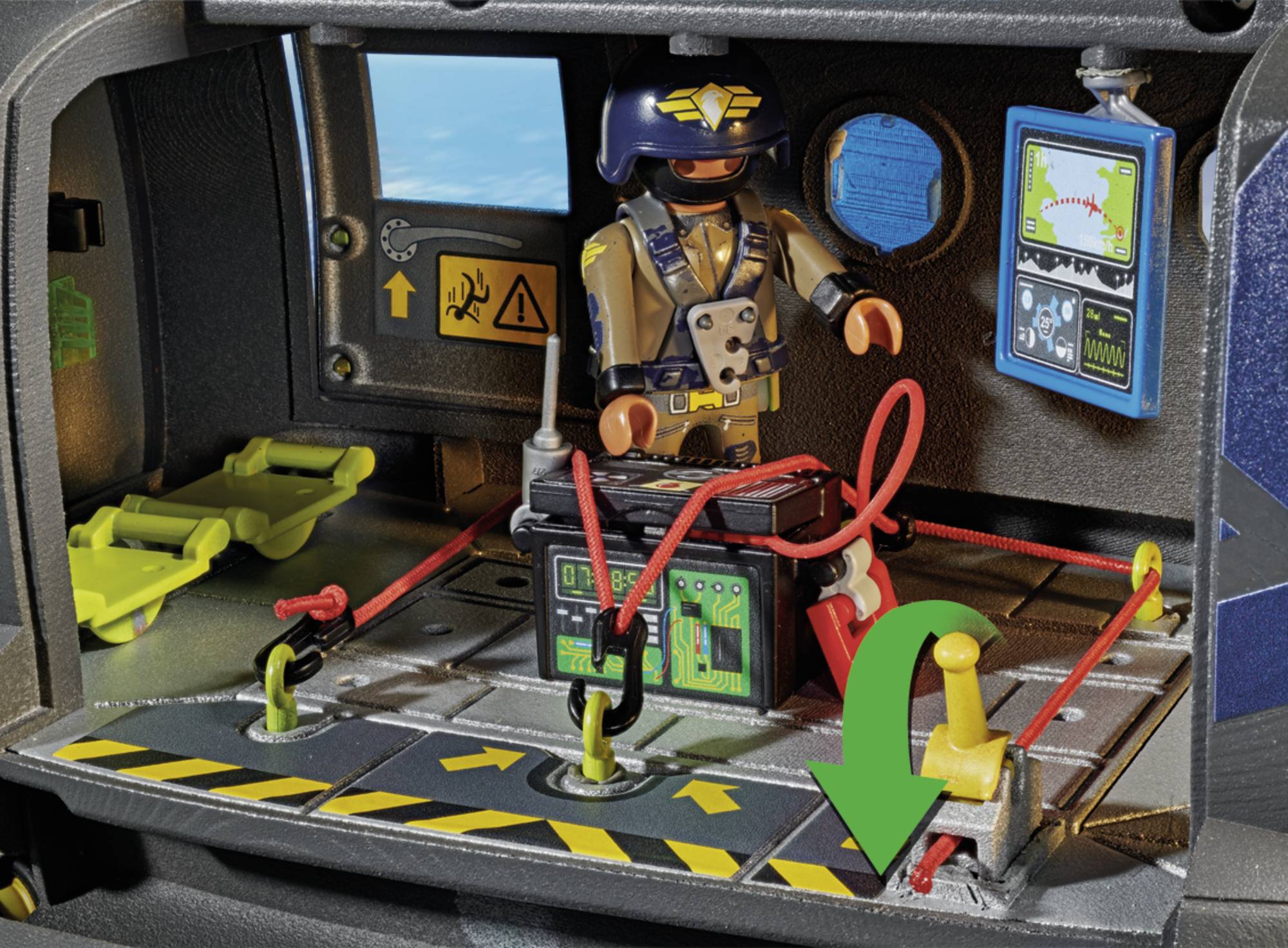 Figurka Playmobil przedstawiająca technika stoi w kokpicie śmigłowca, wyposażonym w panel sterowania, czerwone kable i naklejki bezpieczeństwa.