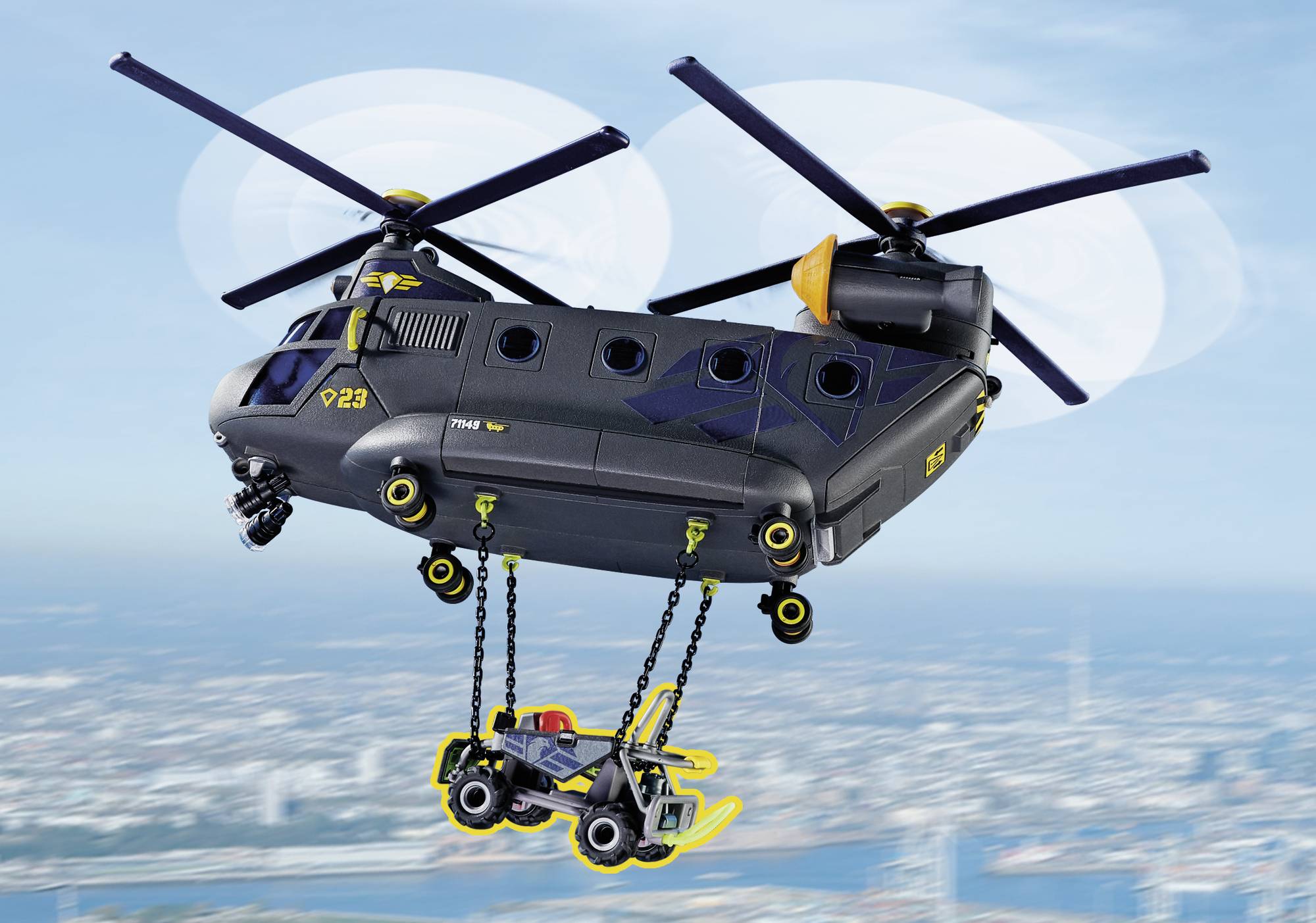 Zabawkowy helikopter transportuje pojazd nad rozmytym krajobrazem. Śmigła wirują, widoczne są żółte akcenty.