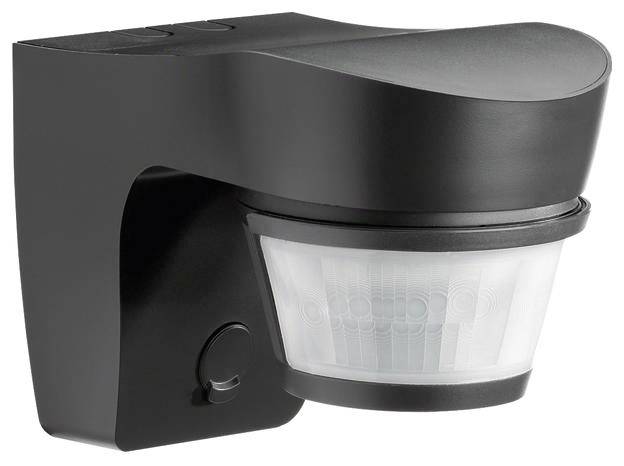 Czarny czujnik ruchu z białym czujnikiem światła, przeznaczony do montażu na ścianach, służący do wykrywania ruchu i włączania systemów oświetleniowych.