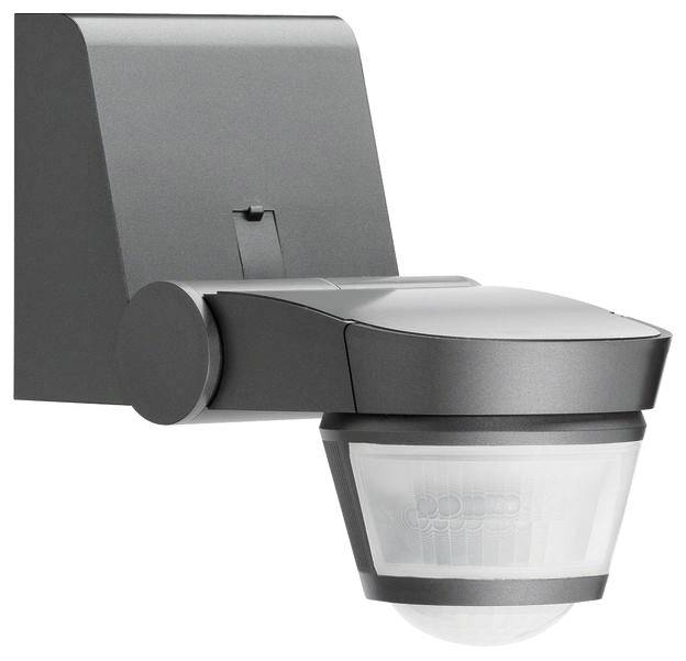 Szary czujnik ruchu zamocowany na uchwycie ściennym. Jest przeznaczony do stosowania na zewnątrz i posiada prostokątny obszar wykrywania.