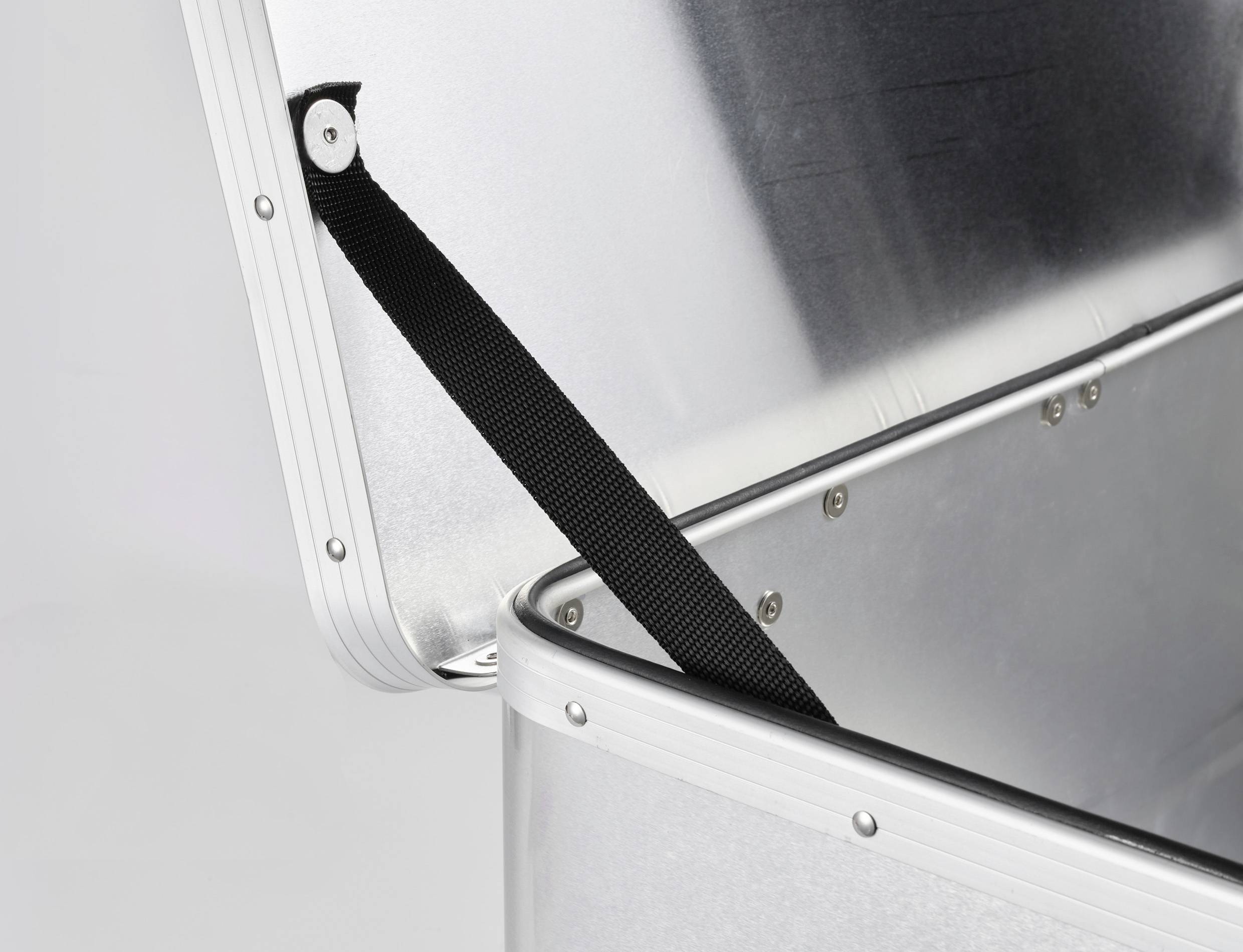 Otwarty aluminiowy kufer z czarnym paskiem przytrzymującym pokrywę, prezentuje solidną konstrukcję i przemysłowe przeznaczenie.