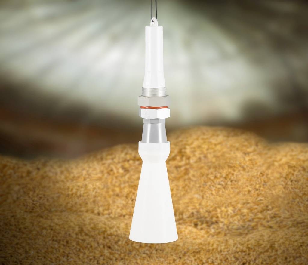 Biały lejek z tworzywa sztucznego i metalu, zamocowany na kablu przed rozmytym tłem w odcieniach brązu.