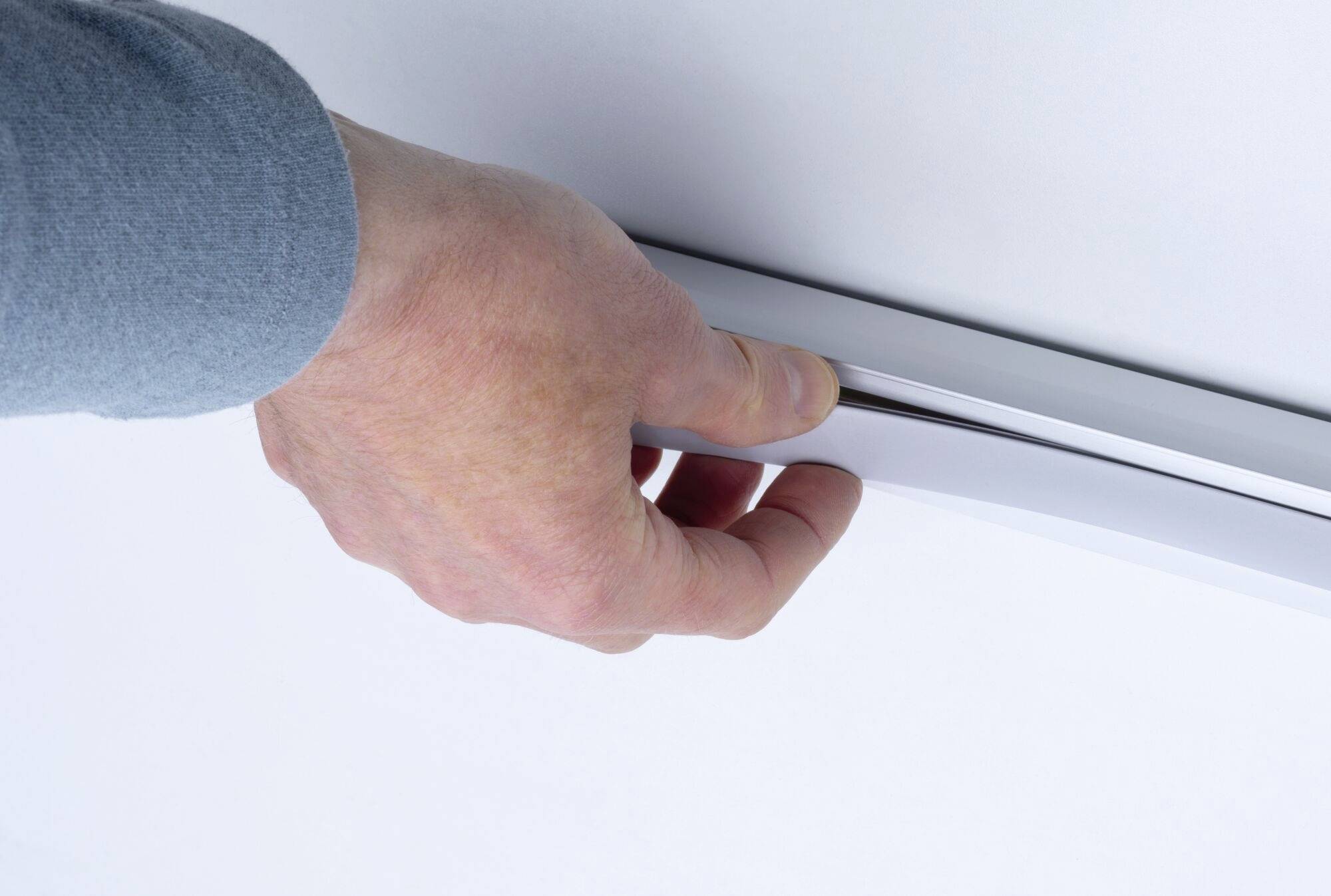 Dłoń w niebieskim rękawie otwiera białą szufladę.