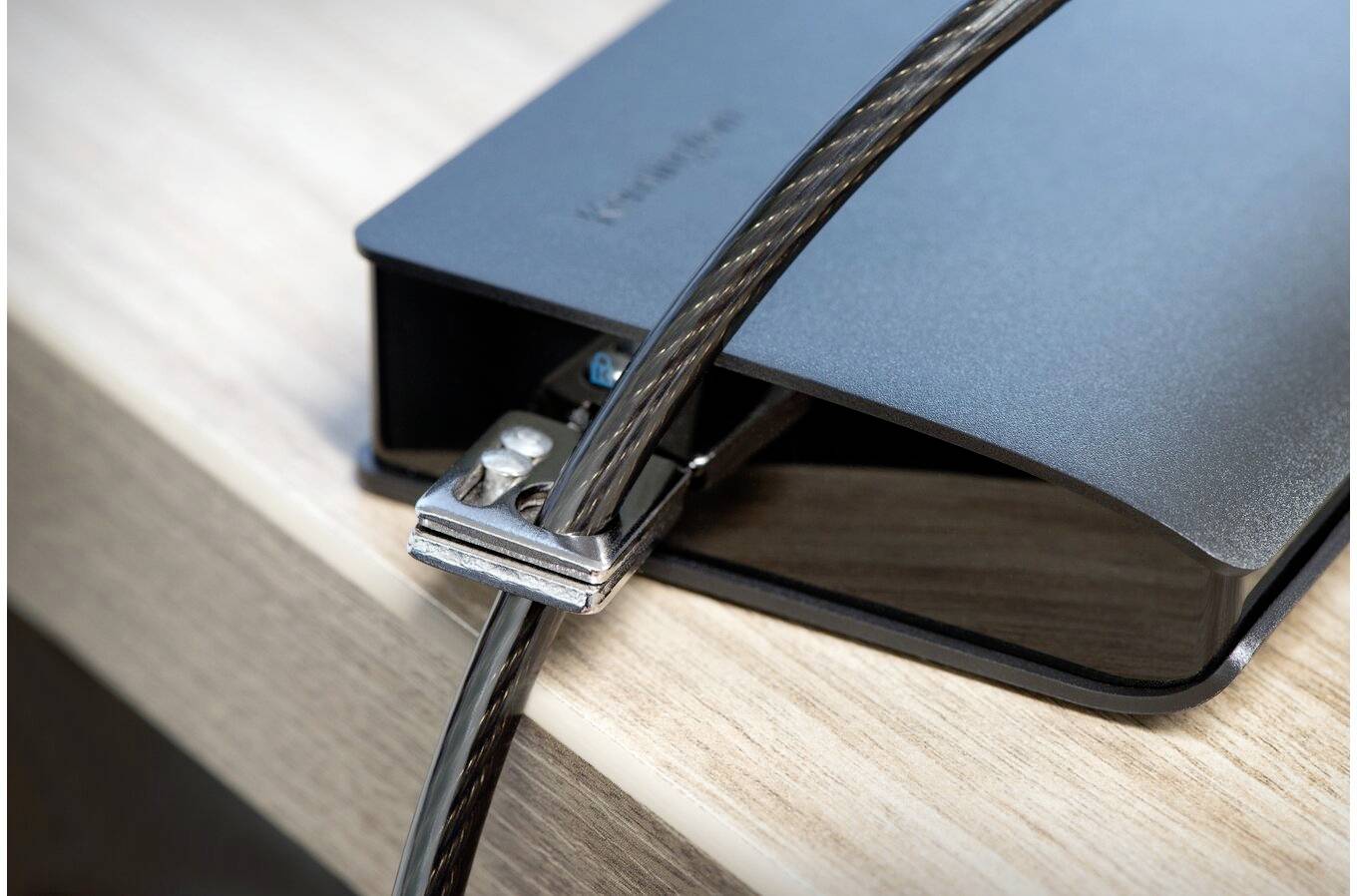 Kabel zabezpieczające laptopa jest przymocowane do krawędzi biurka, aby chronić urządzenie przed kradzieżą.