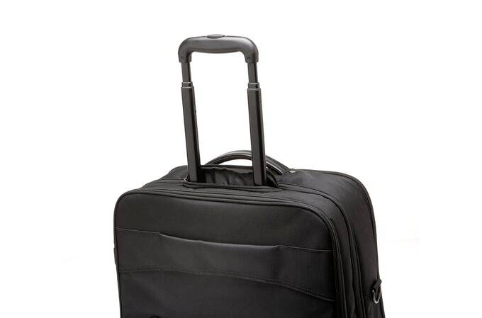 Czarny kufer z wysuniętą teleskopową rączką na białym tle.